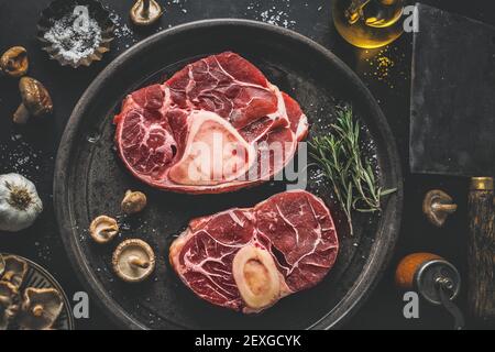 Carne cruda con verdure e spezie su sfondo scuro vintage. Vista dall'alto. Foto Stock