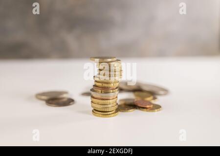 pile di moneta nella parte anteriore e monete nella parte posteriore fuori fuoco isolato su uno sfondo astratto contemporaneo Foto Stock