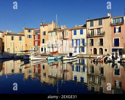 Foto idilliaca di un piccolo porto di Martigues vicino a Marsiglia chiamato specchio d'uccello con case colorate e piccole barche che riflettono acceso Foto Stock