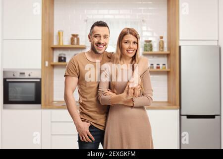 Giovane coppia allegra in posa all'interno di una cucina moderna Foto Stock