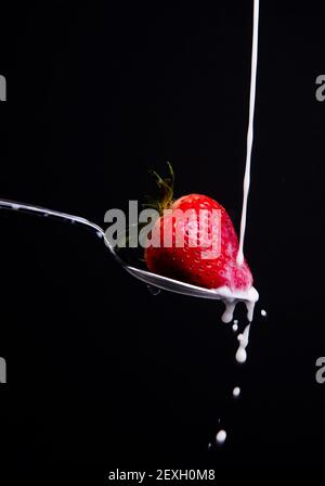 Cibo crudo frutta latte di fragola schizzi sul cucchiaio Foto Stock