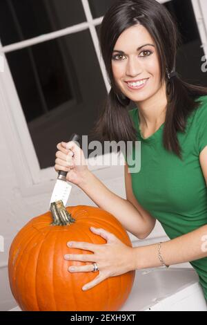 Excited donna il taglio di intagliare la Zucca di Halloween Jack-O-Lantern Foto Stock