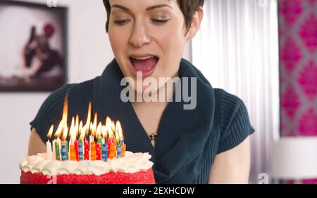 Attraenti Readies femminili per soffiare fuori le candele della torta di compleanno Foto Stock