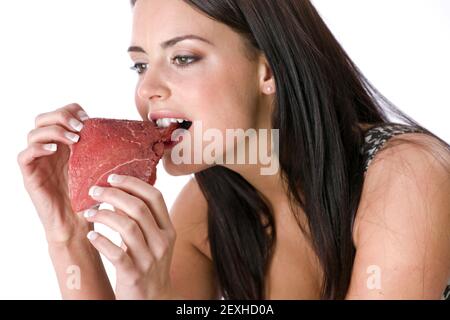 Donna che mangia la carne cruda gnawing Bite con denti Foto Stock