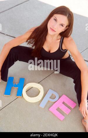 Speranza comunicata in lettere di blocco sul cemento da attraente Donna Foto Stock