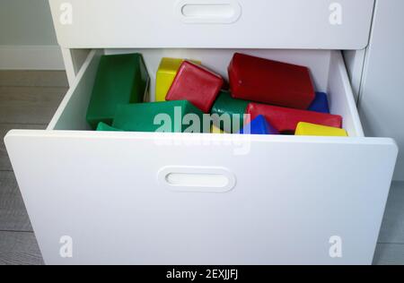 Cubi multicolore in un cassetto di un armadio in una stanza per bambini. Box giochi per bambini con giocattoli per costruzioni. Cubi per bambini per il gioco. Foto Stock