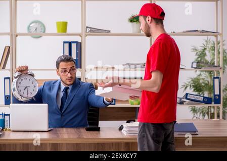 Giovane uomo che consegna la pizza in ufficio in gestione del tempo concetto Foto Stock