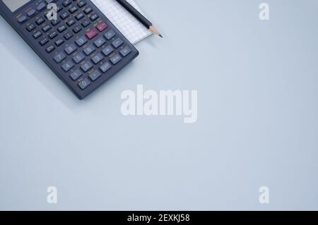 Un primo piano di una calcolatrice scientifica su un notebook e. matita sulla superficie grigio pastello per uno spazio di copia Foto Stock