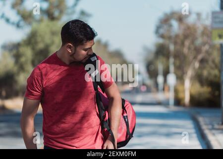 Un primo piano di un maschio ispanico con uno zaino andare in palestra Foto Stock