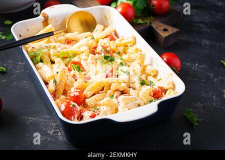 Fetapasta. Ricetta di tendenza della Feta virale cuocere la pasta fatta di pomodori ciliegini, formaggio feta, aglio ed erbe in un piatto di casseruola. Foto Stock