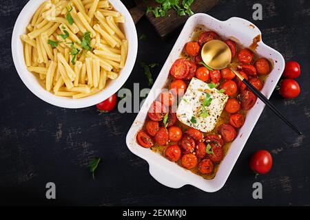 Fetapasta. Ricetta di tendenza della Feta virale cuocere la pasta fatta di pomodori ciliegini, formaggio feta, aglio ed erbe in un piatto di casseruola. Vista dall'alto, sopra, centro benessere con copia Foto Stock