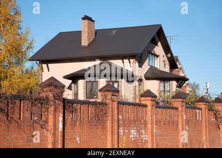 Un cottage a due piani in mattoni rossi con una recinzione Foto Stock