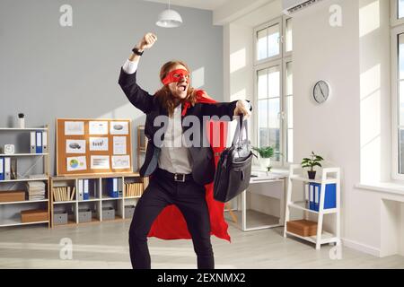 Felice lavoratore divertente in super eroe cape danzare e divertirsi mentre lascia l'ufficio Foto Stock