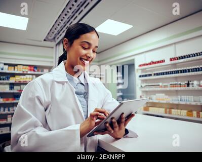 Donna allegra che lavora in farmacia utilizzando un tablet digitale touchscreen Foto Stock