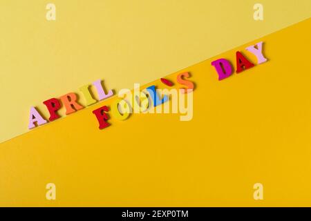 Lettere in legno il primo aprile su sfondo giallo. Il concetto di festa, aprile Fool's Day, il primo di aprile. Foto Stock