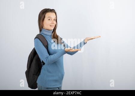 Immagine di una giovane ragazza sorridente modello con zaino in mostra mani Foto Stock