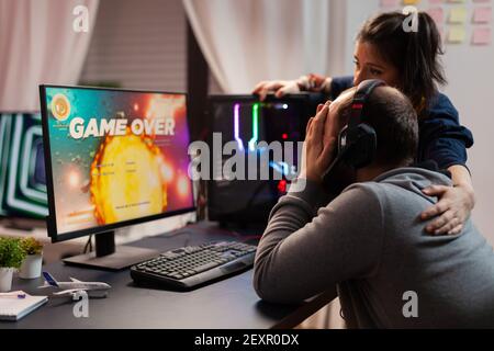 Vista laterale del gioco per una coppia di giocatori professionisti, giocando giochi sparatutto spazio. Sconfitto uomo in streaming online cyber performing durante il torneo di gioco Foto Stock