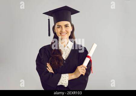 Ritratto di studio di felice laureato intelligente tenuto il suo diploma e sorridendo alla macchina fotografica Foto Stock