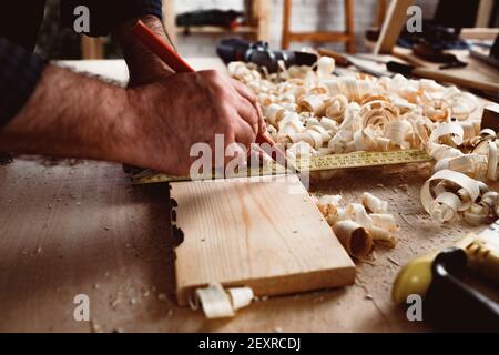 Il carpentiere fa segni a matita su una tavola di legno Foto Stock