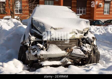 Auto dopo un incidente in un parcheggio, tronco rotto, coperto di neve Foto Stock