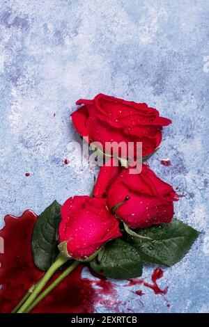 Rose rosse e sangue su sfondo blu con spazio per la copia e spazio per il testo Foto Stock