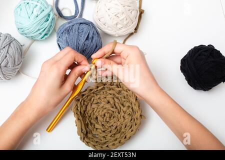 Palle di filato di colore diverso. Le mani dei bambini sono accovacciate e la vista del filo da sopra sul tavolo bianco Foto Stock