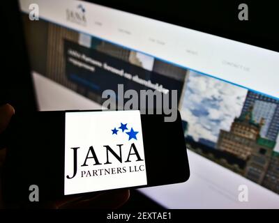 Persona che detiene smartphone con il logo della società di investimento statunitense JANA Partners LLC sullo schermo di fronte al sito Web. Mettere a fuoco il display del telefono. Foto Stock