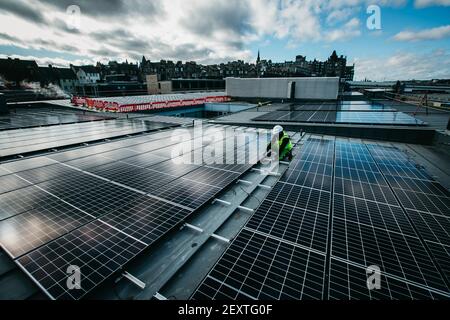 Operatore che monta pannelli solari sul tetto degli uffici del City Council di Edimburgo, Waverley Court, Edimburgo, UK. Foto Stock