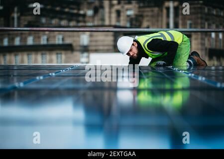 Operatore che monta pannelli solari sul tetto degli uffici del City Council di Edimburgo, Waverley Court, Edimburgo, UK. Foto Stock