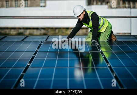 Operatore che monta pannelli solari sul tetto degli uffici del City Council di Edimburgo, Waverley Court, Edimburgo, UK. Foto Stock