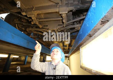 Stagecoach Garage, Kilmarnock, Scozia, Regno Unito 08 aprile 2018. Una giornata aperta al deposito con vari autobus e pullman in mostra, oltre a disservizi e negozi. Una carrozza trainata da cavalli ha dato giri intorno al cortile del garage. La foto mostra un ragazzino che ispetta un autobus dal basso Foto Stock