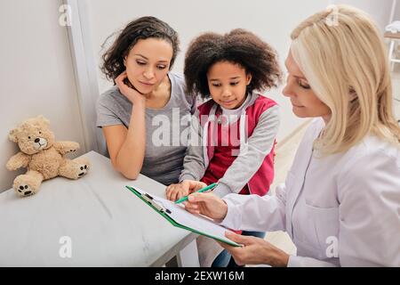 Madre afroamericana con sua figlia nell'ufficio dello psicologo infantile. Psicologo dei bambini che si prende cura della salute mentale del bambino Foto Stock