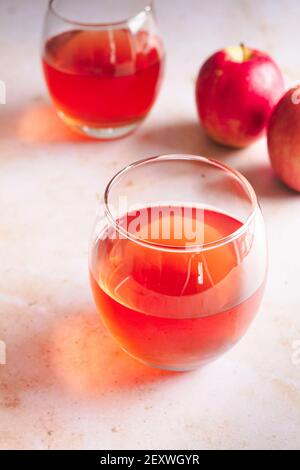 Due bicchieri di mela Pink Lady con due mele fresche sullo sfondo. Foto Stock