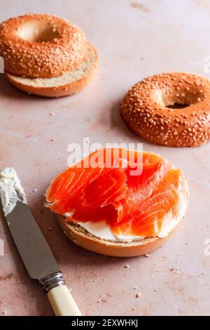 Bagel a metà spalmato con formaggio cremoso e condito con trota affumicata. Foto Stock