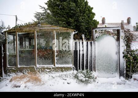 Giardino coperto di neve cancello e serra Foto Stock