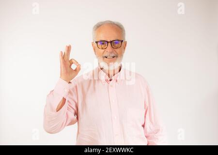 felice positivo bel vecchio uomo mostra ok segno su sfondo bianco. Foto Stock