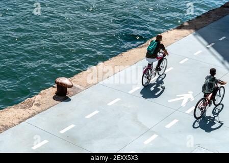 Santander, Spagna - 13 settembre 2020: Padre e figlio in bicicletta lungo la passeggiata sul mare. Vista dall'alto. Foto Stock