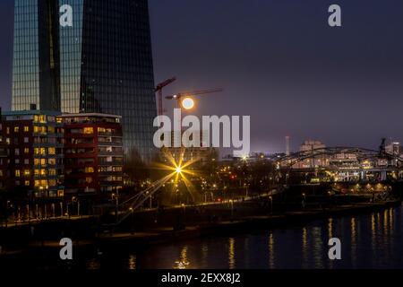 Vista sul fiume meno fino alla Banca Centrale europea a Francoforte in una notte fredda in inverno con la luna piena in aumento. Foto Stock