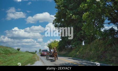 Ronks, Pennsylvania, 2020 luglio - una coppia Amish in un cavallo aperto e buggy in un giorno di sole Foto Stock