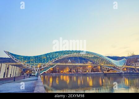 Il ponte di pace sul fiume Kura a Tbilisi nel crepuscolo Foto Stock