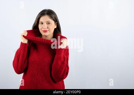 Foto ritratto di una giovane donna modello in rosso caldo maglione in piedi e in posa Foto Stock