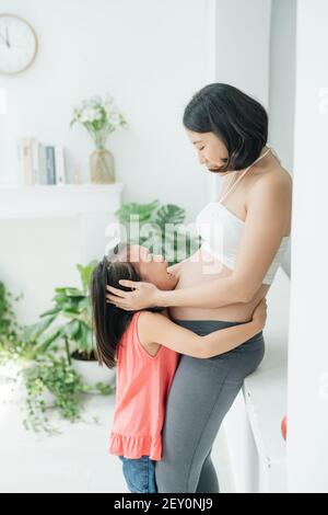 Non voglio fratello. Triste piccola figlia guardando la sua gravidanza mamma pancia, bambino piangere per che non vogliono i gemelli, famiglia problema, chiudere fino Foto Stock