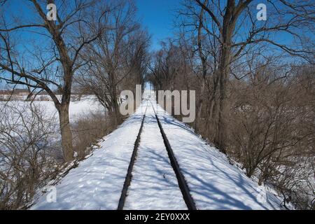 Vista dei binari della ferrovia che corrono attraverso la campagna coperta Nella neve Foto Stock