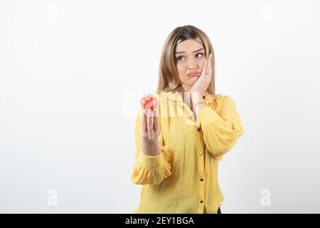 Donna delusa che tiene il pomodoro rosso su sfondo bianco Foto Stock