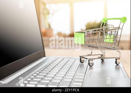 Concetto di shopping online. Carrello su laptop. Carrello per laptop e drogheria. Concetto di acquisto a casa Foto Stock