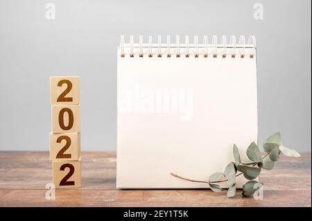 2022 tempo per un nuovo inizio. Piano parole e 2022 cubetti di legno sfondo tabella. New Year. Piani per il 2022, spazio per il tuo testo su blocco note, mockup calenda Foto Stock