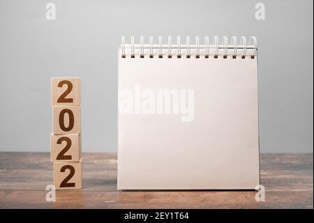 Calendario 2022 mockup. Testo 2022 su cubi di legno. Spazio per il tuo testo su blocco note, calendario mockup. Nuovo anno. Concetto di avvio Foto Stock