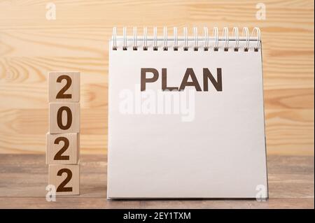 2022 tempo per un nuovo inizio. Piano parole e 2022 cubetti di legno sfondo tabella. New Year. Piani per il 2022, spazio per il tuo testo su blocco note, mockup Foto Stock