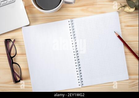 Area di lavoro con blocco note con matita e schermo tablet vuoto per posizionare il testo e il design. blocco note e una tazza di caffè su un desktop in legno Foto Stock
