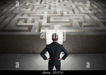 L'uomo d'affari sta cercando il percorso di uscita nel labirinto. Strategia e concetto di decisione. Vista da dietro. Foto Stock